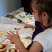 Shows an image of a little girl making mini pizzas