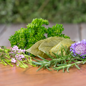 Shows an image of fresh herbs on a cutting board, including Rosemary, Thyme, parsley, and bay leaves
